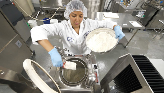 woman scooping a milk product from a container